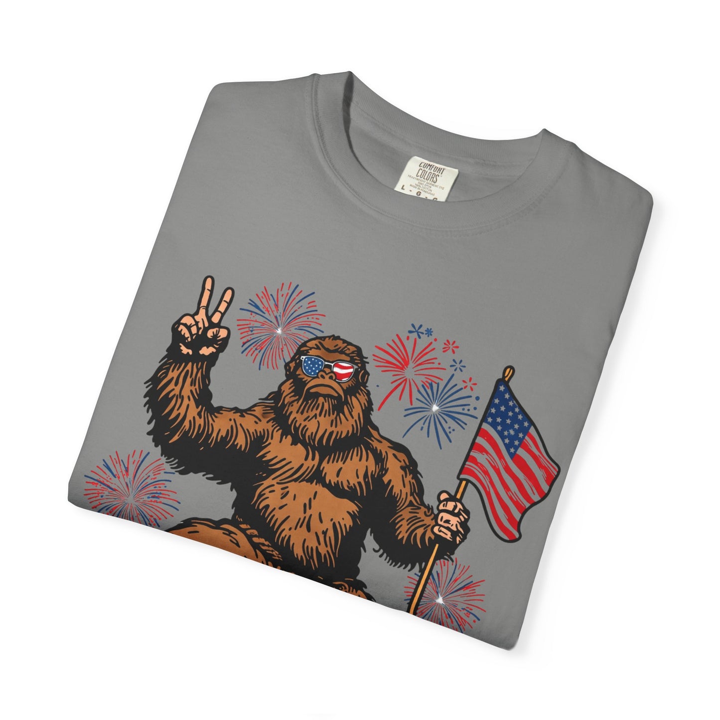 Patriotic Sasquatch Graphic T-Shirt — Bigfoot Holding American Flag, Fireworks 4th of July Tee