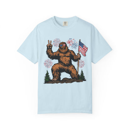 Patriotic Sasquatch Graphic T-Shirt — Bigfoot Holding American Flag, Fireworks 4th of July Tee