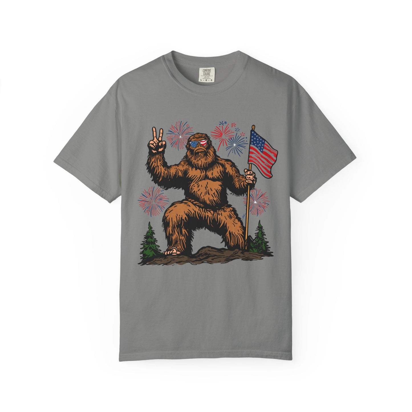 Patriotic Sasquatch Graphic T-Shirt — Bigfoot Holding American Flag, Fireworks 4th of July Tee