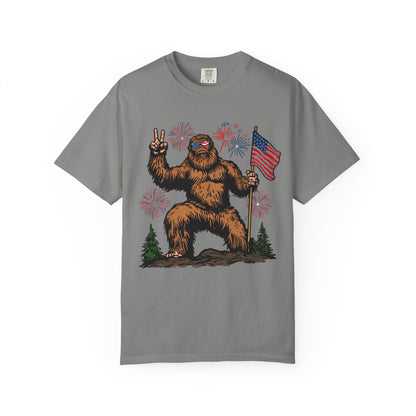 Patriotic Sasquatch Graphic T-Shirt — Bigfoot Holding American Flag, Fireworks 4th of July Tee